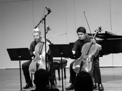 Daniel and a student performing a cello duo on stage